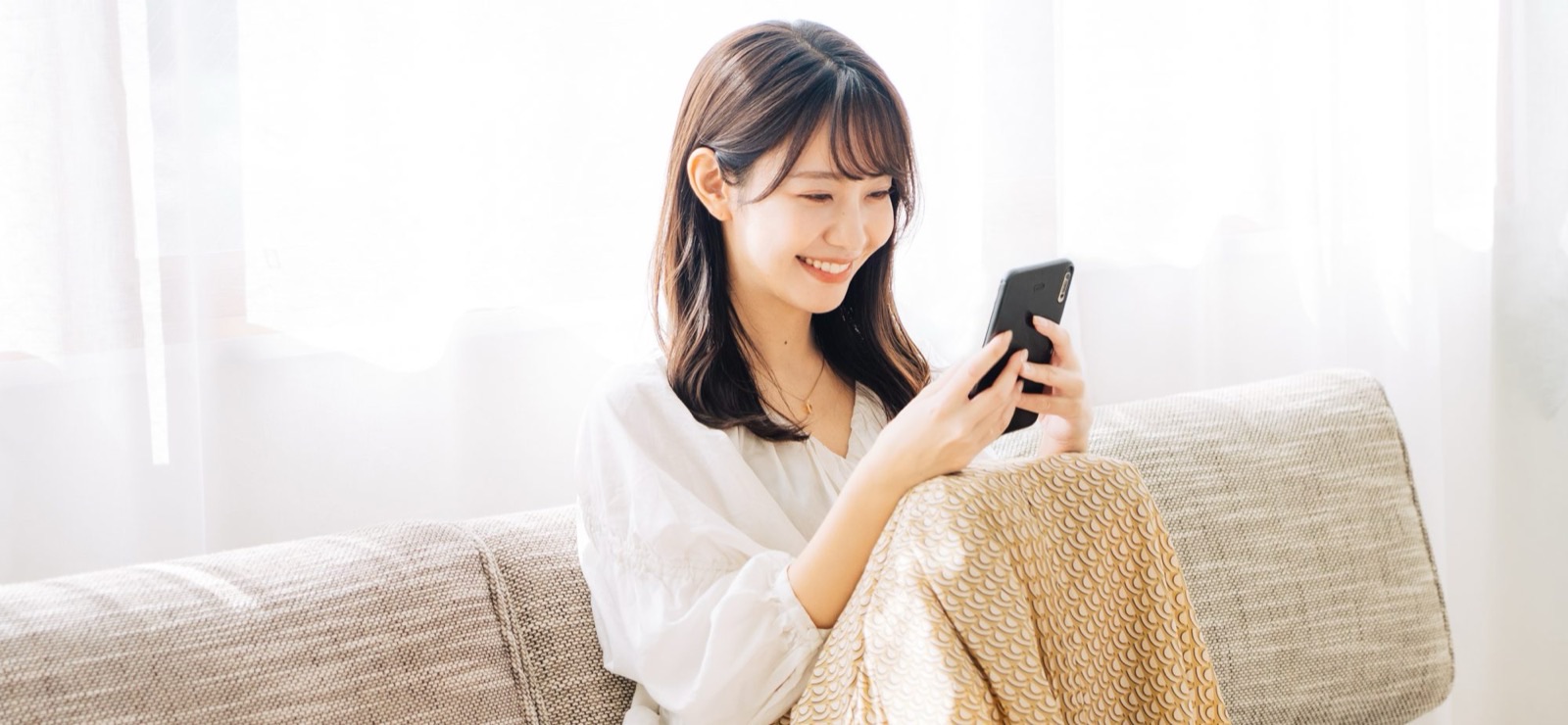 スマートフォンを見ながらくつろぐ女性